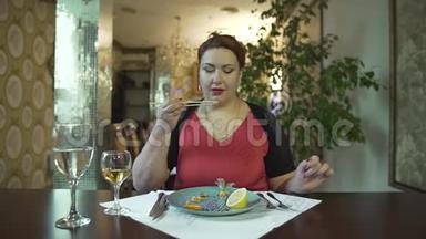 美丽的中年黑发女人穿着红色连衣裙，独自一人在<strong>高档餐厅</strong>用筷子吃食物